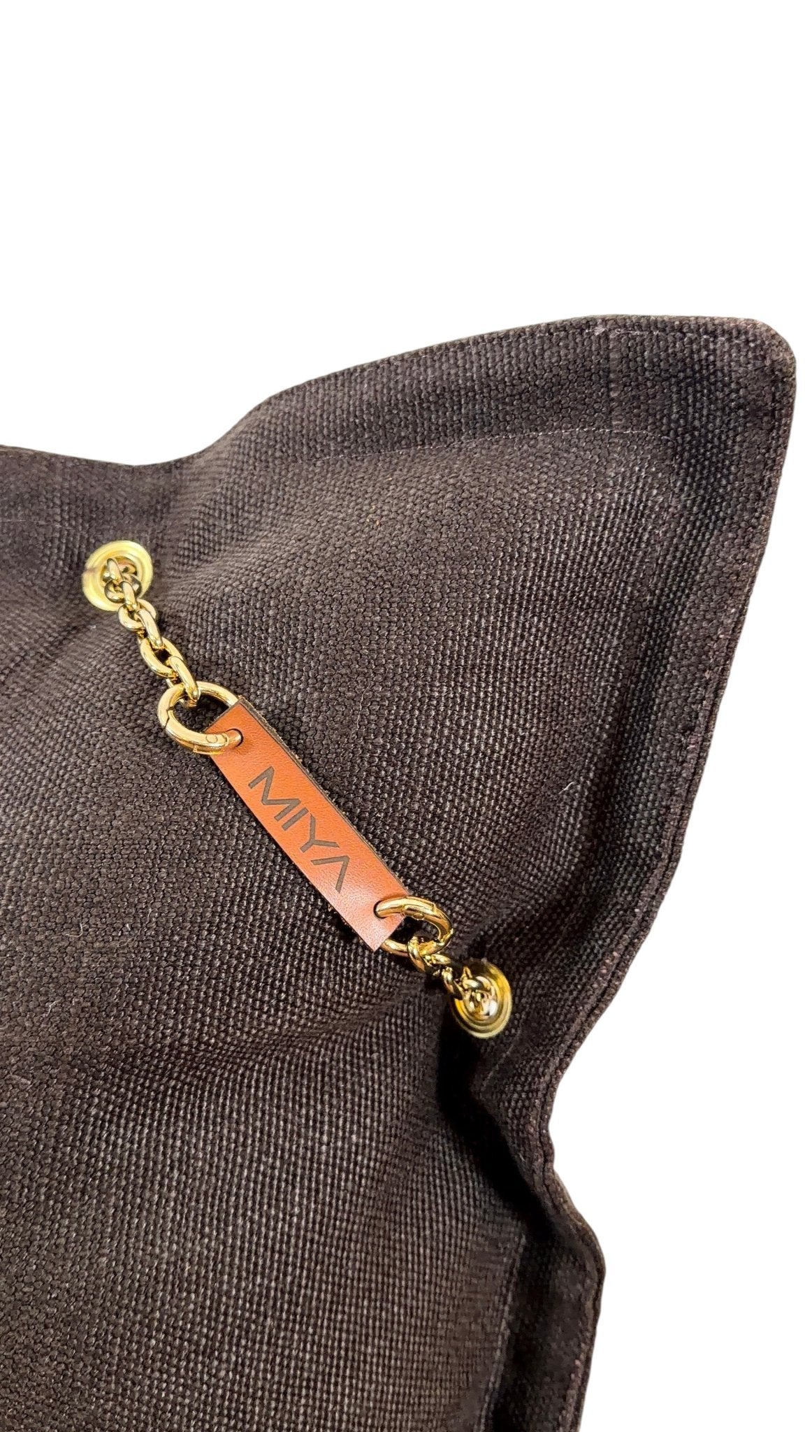 Détail coussin lin chocolat avec signature cuir MIYA et pampille ornée de poids Ashanti et perles – MIYA