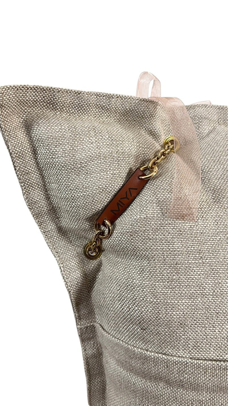 Détail coussin lin beige avec signature cuir MIYA et chaîne dorée – MIYA