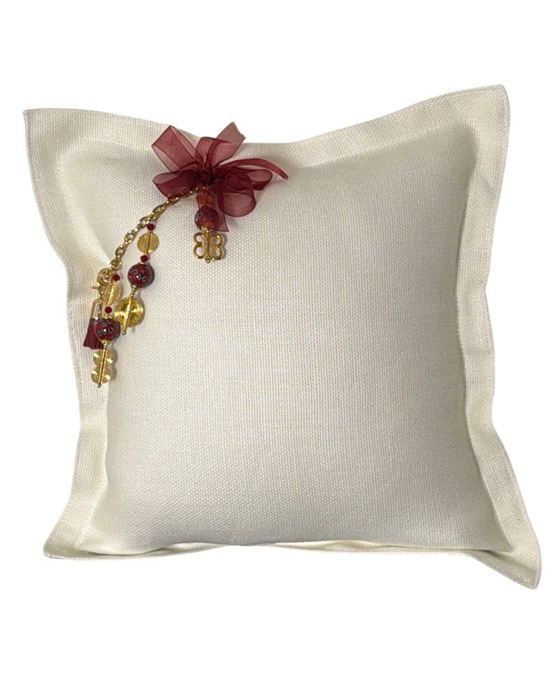 Coussin artisanal blanc MIYA en lin avec pampille signature ZANZIBAR No.48, perles rouges, détails dorés et ruban bordeaux.