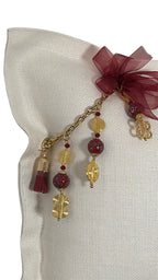 Détail artisanal MIYA avec ruban bordeaux, perles rouges et finitions dorées inspirées des poids Ashanti.