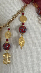 Détail de la pampille MIYA avec perles africaines rouges, poids Ashanti dorés et chaîne décorative.