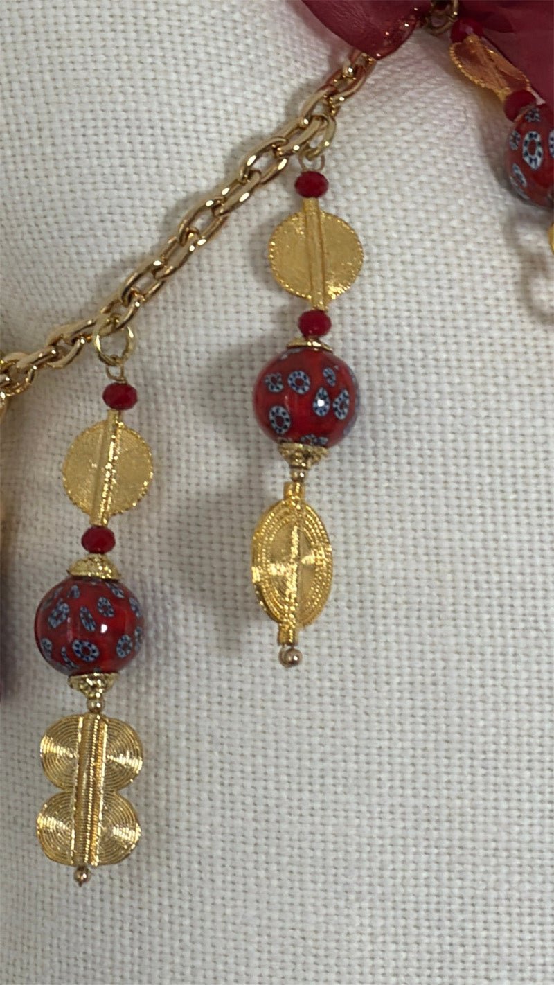 Détail de la pampille MIYA avec perles africaines rouges, poids Ashanti dorés et chaîne décorative.