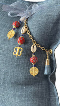 Close-up of the MIYA signature tassel with African beads, cowries and Ashanti weights on heavy blue linen.