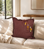 Coussin en lin lourd prune MIYA avec pampille signature, perles safran et poids Ashanti dans un salon contemporain