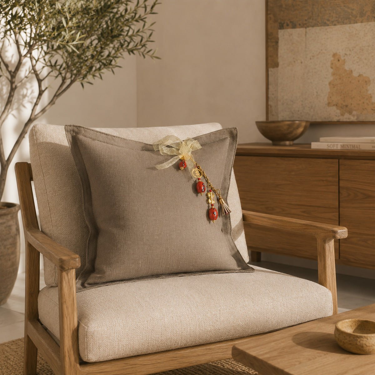 Coussin décoratif en lin lourd grège fait main sur fauteuil contemporain en chêne, avec pampille signature MIYA.
