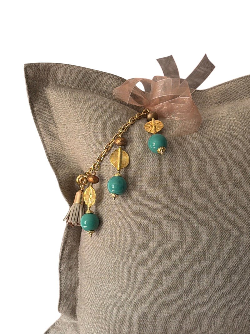 Détail du coussin en lin grège avec pampille signature vert d'eau MIYA