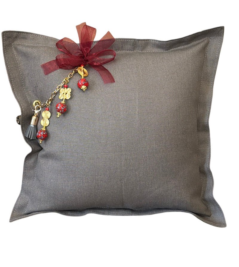 Grey heavy linen throw pillow with MIYA's signature tassel featuring red African beads and traditional Ashanti weights.