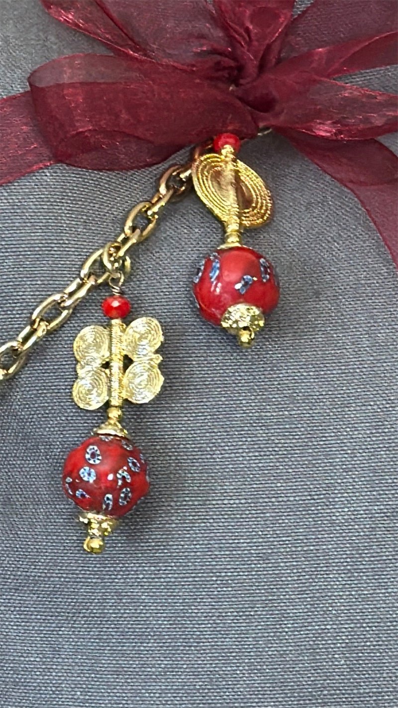 Detail of MIYA's signature tassel featuring red African beads and handcrafted brass Ashanti weights.