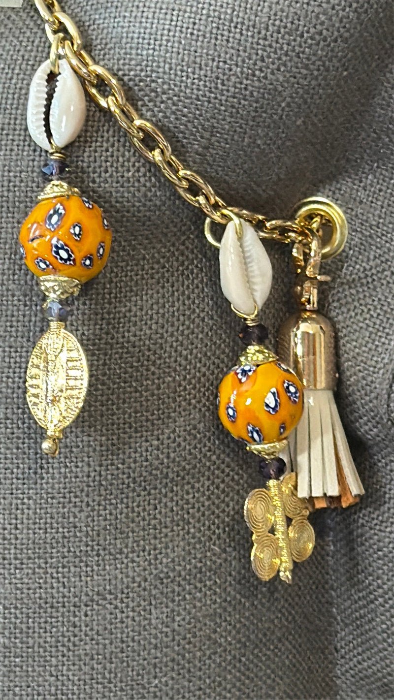 Détail de la signature MIYA avec perles africaines jaunes, cauris et symboles Ashanti.