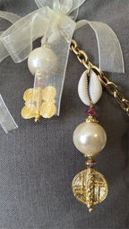 Détail de la signature MIYA avec perles nacrées, cauris et symboles Ashanti.