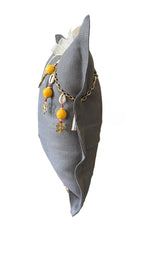 Vue de profil du coussin en lin gris BALI No.69 avec chaîne décorative et pampille signature MIYA.