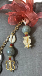 Détail de la signature MIYA avec perles grises, cauris et symboles Ashanti.