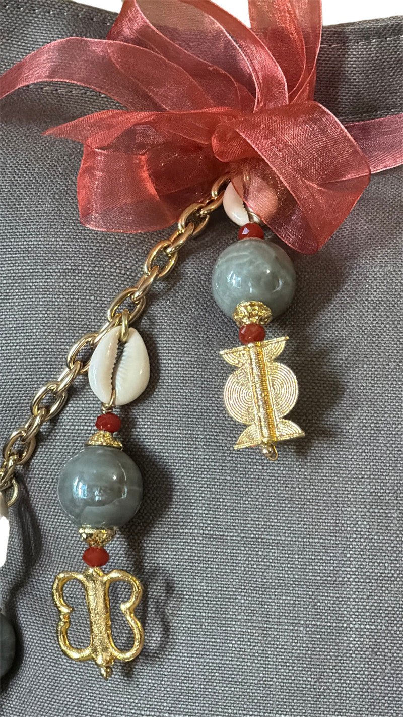 Détail de la signature MIYA avec perles grises, cauris et symboles Ashanti.