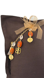 Coussin en lin lourd marron MIYA avec pampille signature, perles artisanales orange et poids Ashanti dorés.