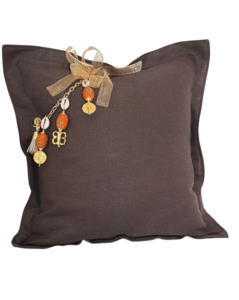 Coussin carré en lin lourd marron MIYA avec pampille signature, cauris et perles orange artisanales.