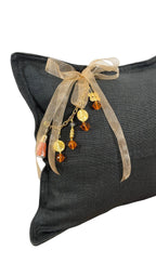 Coussin en lin MIYA anthracite en angle avec pampille signature ornée de poids Ashanti et perles artisanales
