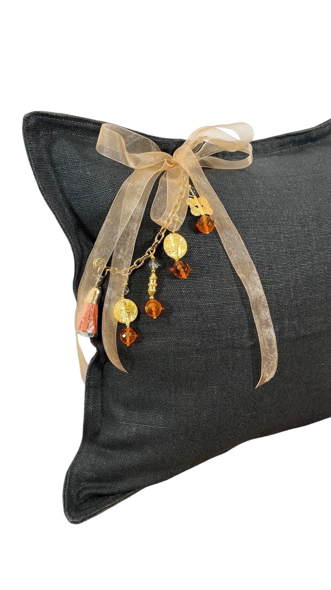 Coussin en lin MIYA anthracite en angle avec pampille signature ornée de poids Ashanti et perles artisanales