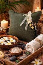 Coussin lin vert olive avec pampille signature ornée de poids Ashanti, ambiance spa bohème – MIYA