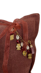 Gros plan sur la pampille MIYA avec poids Ashanti et perles sur coussin rose sienne.