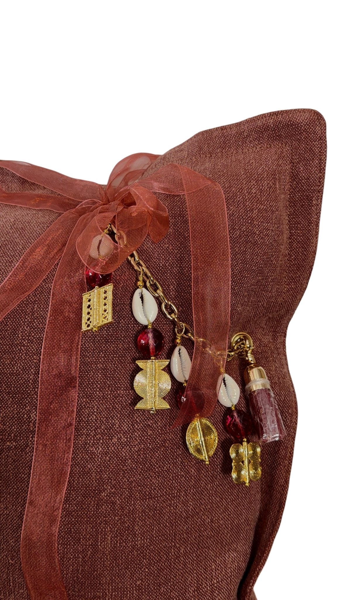 Gros plan sur la pampille MIYA avec poids Ashanti et perles sur coussin rose sienne.