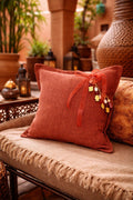 Coussin rose sienne avec pampille signature MIYA, ornée de poids Ashanti et perles, dans un décor inspiré de Marrakech.