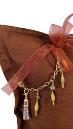 Détail du coussin marron avec ruban pampille signature MIYA ornée de poids Ashanti et perles, style bohème chic raffiné