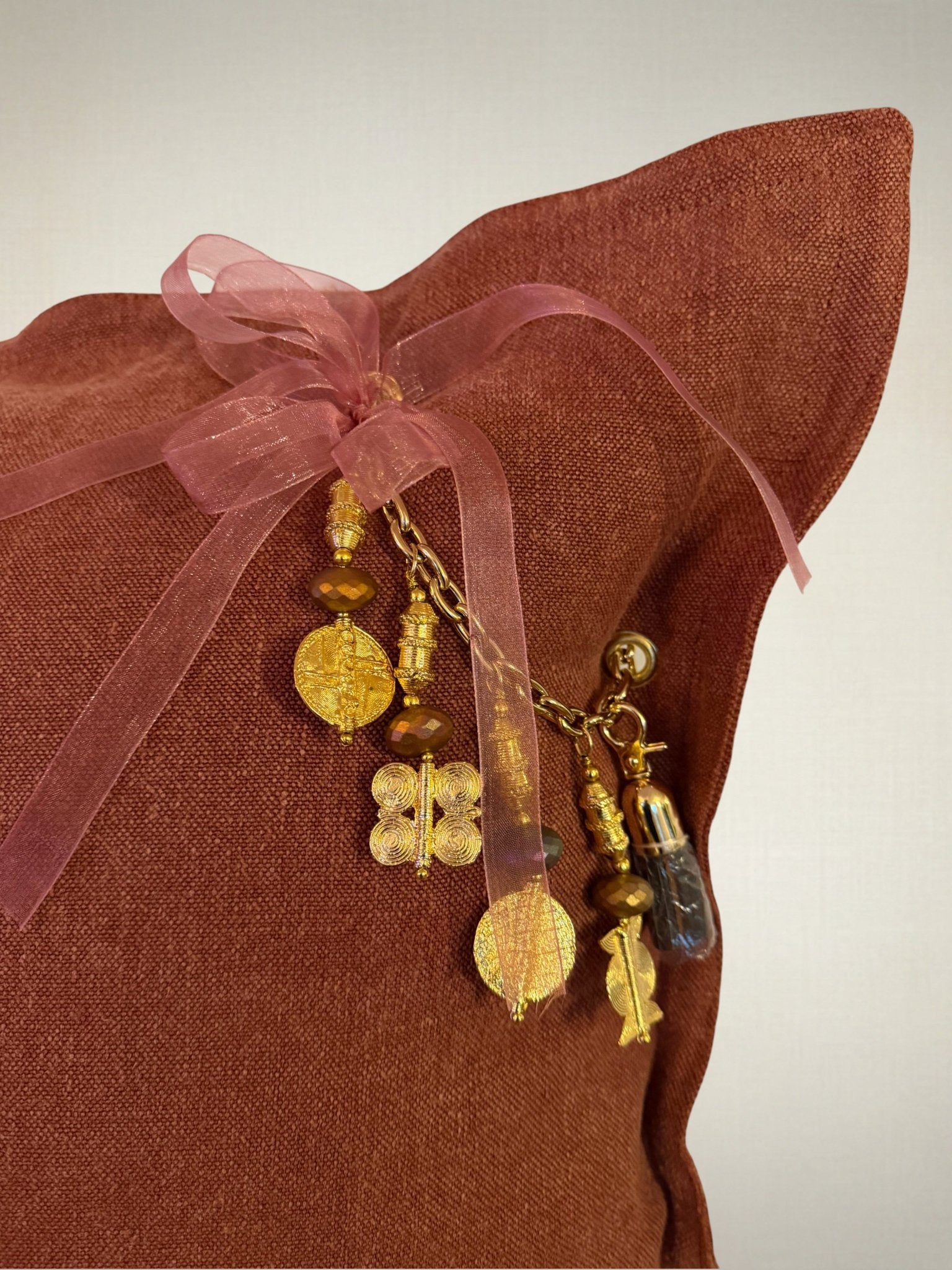 Détail de la pampille artisanale du coussin en lin rouille SIERRA by MIYA, perles et finitions faites main