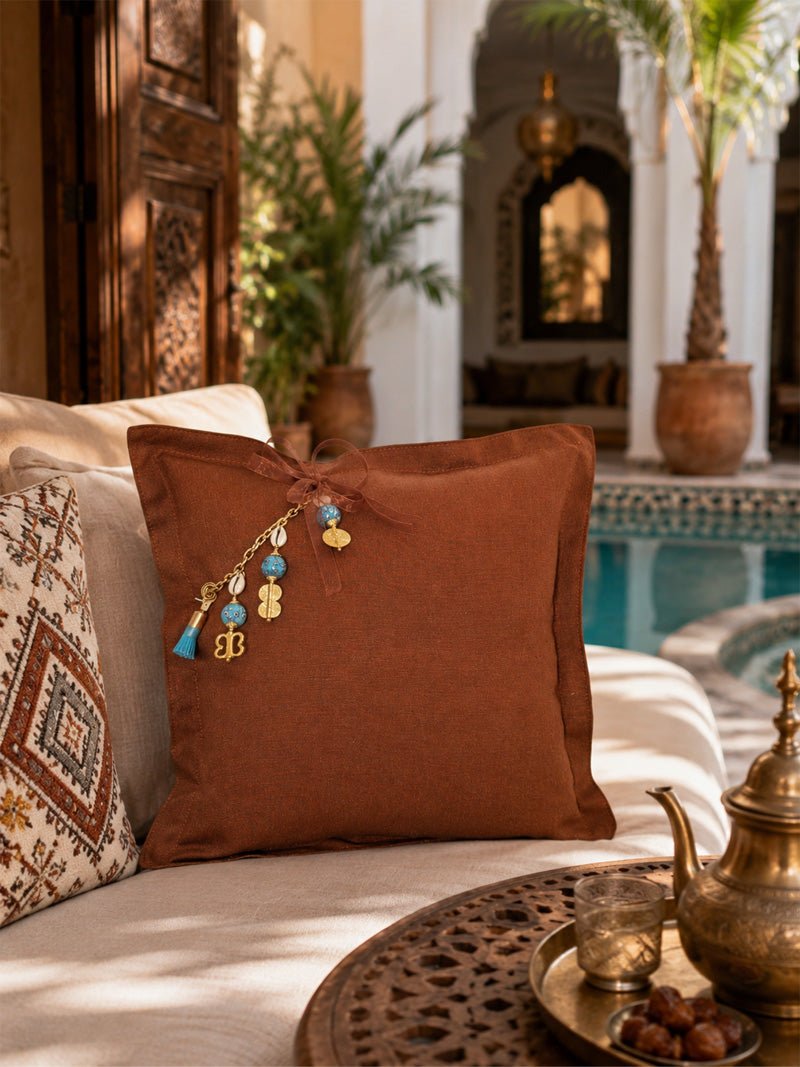 Coussin décoratif MIYA MARRAKECH No.49 en lin lourd terracotta mis en scène dans un riad marocain contemporain, posé sur une banquette écrue au bord d’un bassin.