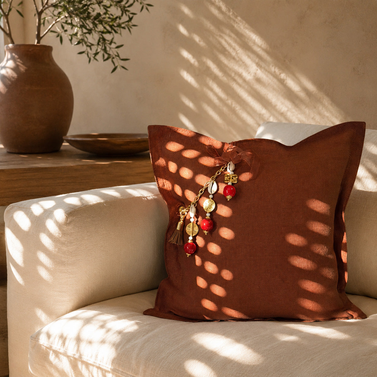 Coussin décoratif en lin terracotta MIYA sur fauteuil contemporain baigné de lumière naturelle.