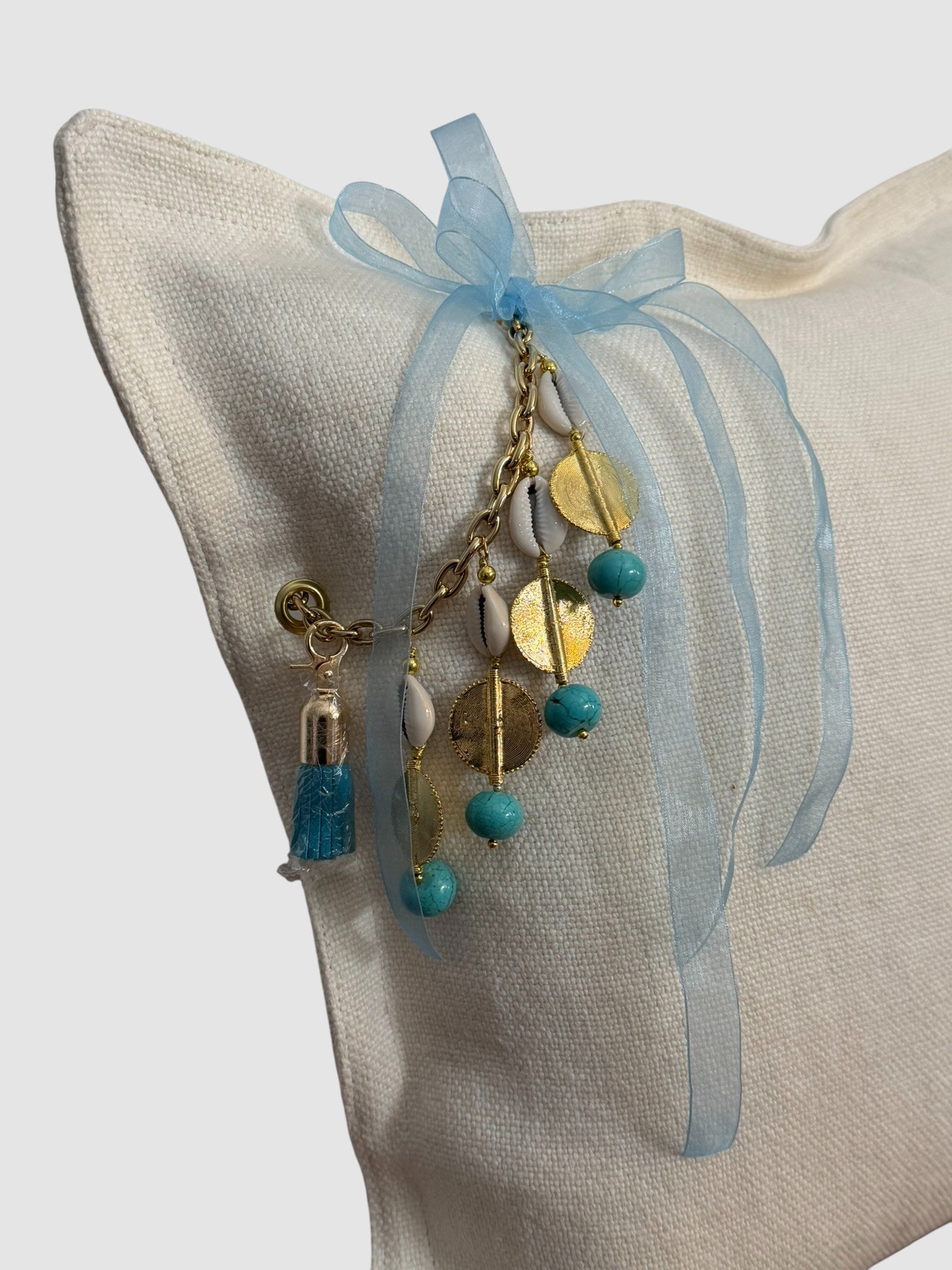 Détail de la pampille artisanale turquoise sur coussin en lin blanc SIERRA by MIYA.
