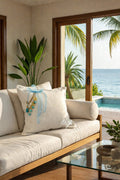 Coussin décoratif en lin blanc avec pampille turquoise, collection SIERRA by MIYA, sur canapé dans un intérieur lumineux.