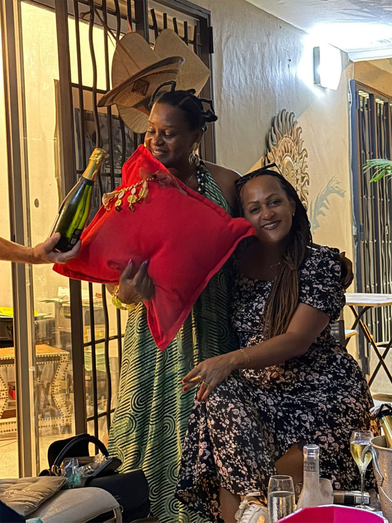 Une femme serre un coussin rouge MIYA dans ses bras, une autre assise à côté sourit