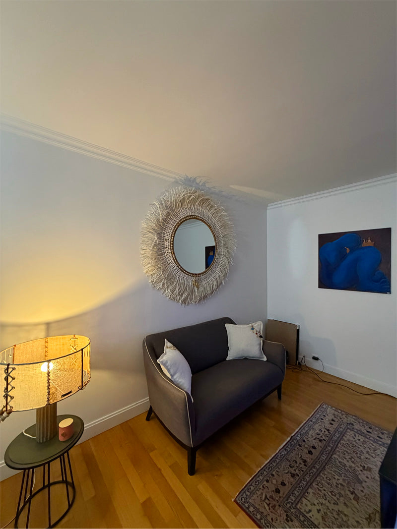 Intérieur parisien avec lampe artisanale corsetée MIYA, miroir XXL en fibres naturelles et ambiance chaleureuse 