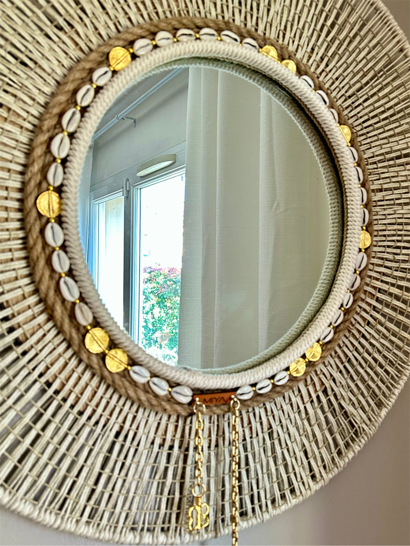 Miroir 40 cm orné de cauris et chaînes avec reflet sur un jardin. MIYA